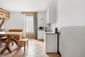 A compact kitchen with a dining area, a built-in microwave, and a kettle.