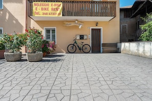 A building with a sign for 'NOLEGGIO E-BIKE RENT' and a contact number.