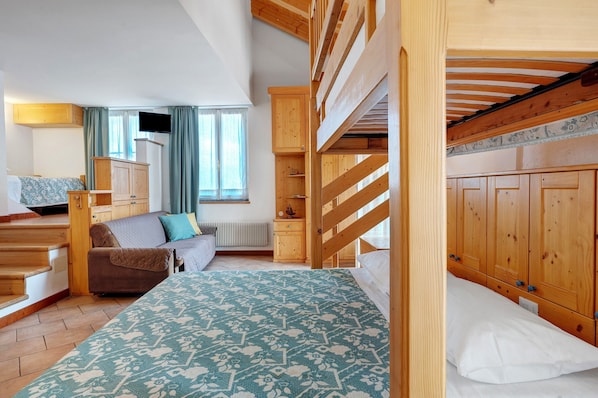 A room with bunk beds, a sofa, a small table, and a cabinet.