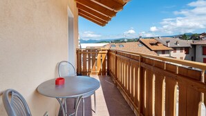 A balcony with a table and chairs, a wooden railing, and a view of buildings and mountains in the distance. - Room 'Vento Alpino Campanile' with Balcony and Wi-Fi (Coredo)