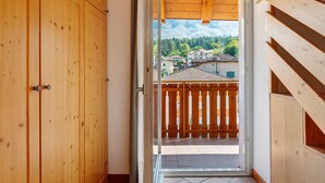 A wooden interior with a view of a balcony and buildings outside. - Room 'Vento Alpino Campanile' with Balcony and Wi-Fi (Coredo)