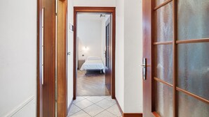 A hallway leading to a bedroom with a bed, a door with a handle, and a tiled floor. - Apartment 'Gianni' with Mountain View, Balcony and Wi-Fi (Coredo)