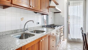 A kitchen with granite countertops, stainless steel sink, wooden cabinets, and a gas stove. - Apartment 'Gianni' with Mountain View, Balcony and Wi-Fi (Coredo)