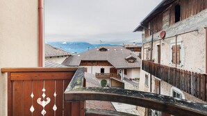 A traditional building with a balcony, a wooden fence, and a view of other buildings and mountains. - Apartment 'Gianni' with Mountain View, Balcony and Wi-Fi (Coredo)