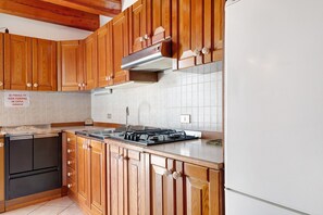 Una cocina con armarios de madera, una estufa y un refrigerador blanco.
