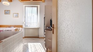 Ein Zimmer mit einem Bett, einem Fenster, einer Heizung, einem Fernseher und einem Schrank.