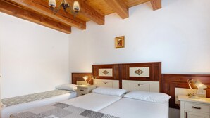 Ein Schlafzimmer mit einem großen Bett, zwei Nachttischen, einem Beistelltisch und einer Holzbalkendecke.