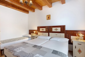 A bedroom with a large bed, two bedside tables, a nightstand, and a wooden ceiling.