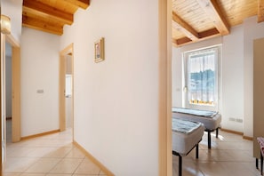 A room with a wooden ceiling, a window with a view, and two beds.