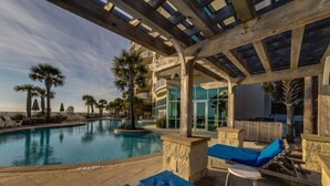 Un área de piscina con sillones de descanso y una pérgola.