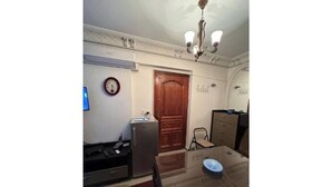 A dining area with a wooden table, chairs, a clock, a refrigerator, and a chandelier. - Amazing studio apartment gleem (Alexandria)