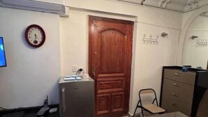 A dining area with a wooden table, chairs, a clock, a refrigerator, and a chandelier. - Amazing studio apartment gleem (Alexandria)