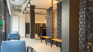 A modern waiting area with blue chairs, a wooden bench, and patterned partitions. - Student Only Market Quarter (Bristol)