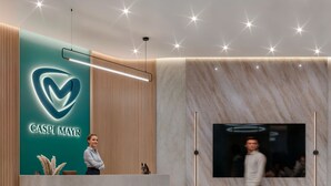 Un área de recepción con diseño moderno, que incluye un mostrador de recepción color turquesa, un panel de pared de listones de madera y una pared de mármol con una pantalla grande.