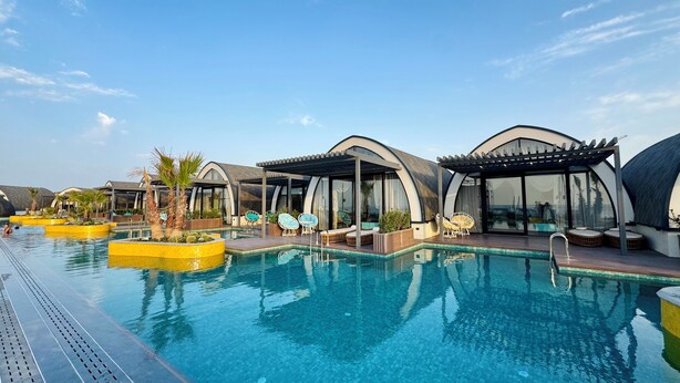 Zona de piscina con arquitectura moderna y curvas, y mobiliario exterior.