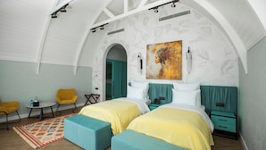 A room with two beds, a small table, two chairs, and a painting on the wall.