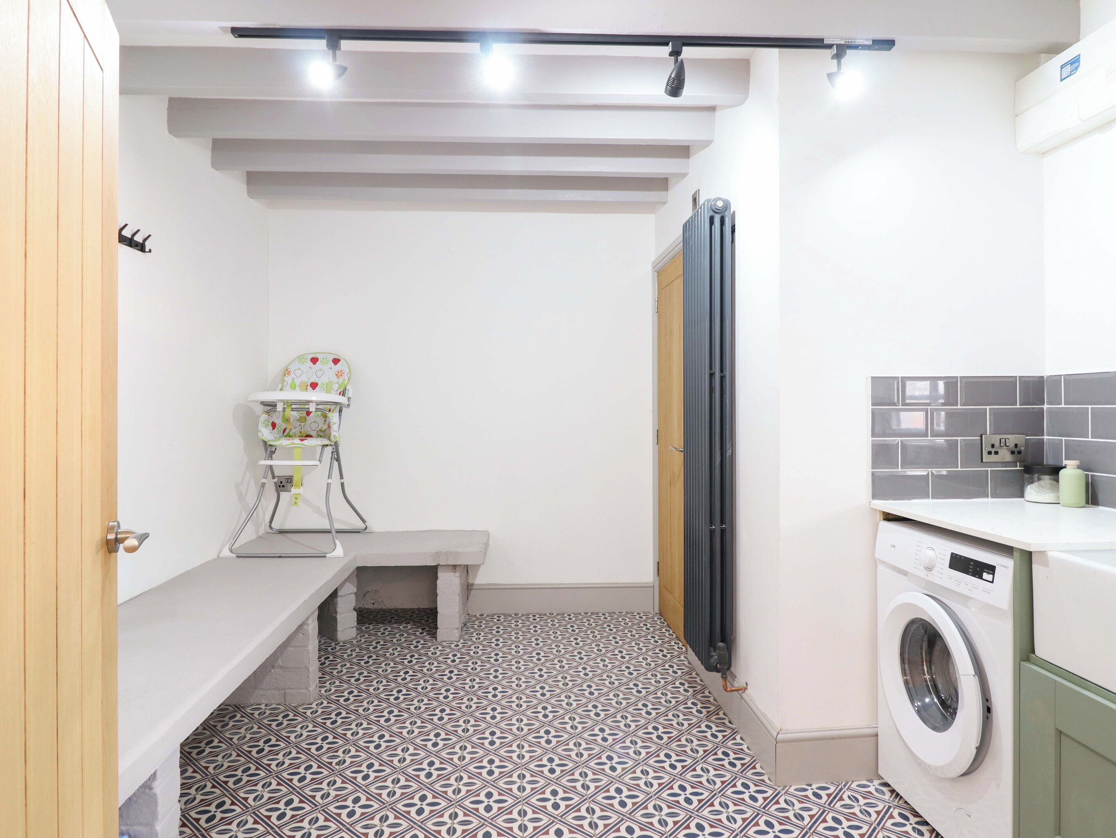 Une petite salle de bain équipée d’un banc, d’un lave-linge et d’un radiateur.