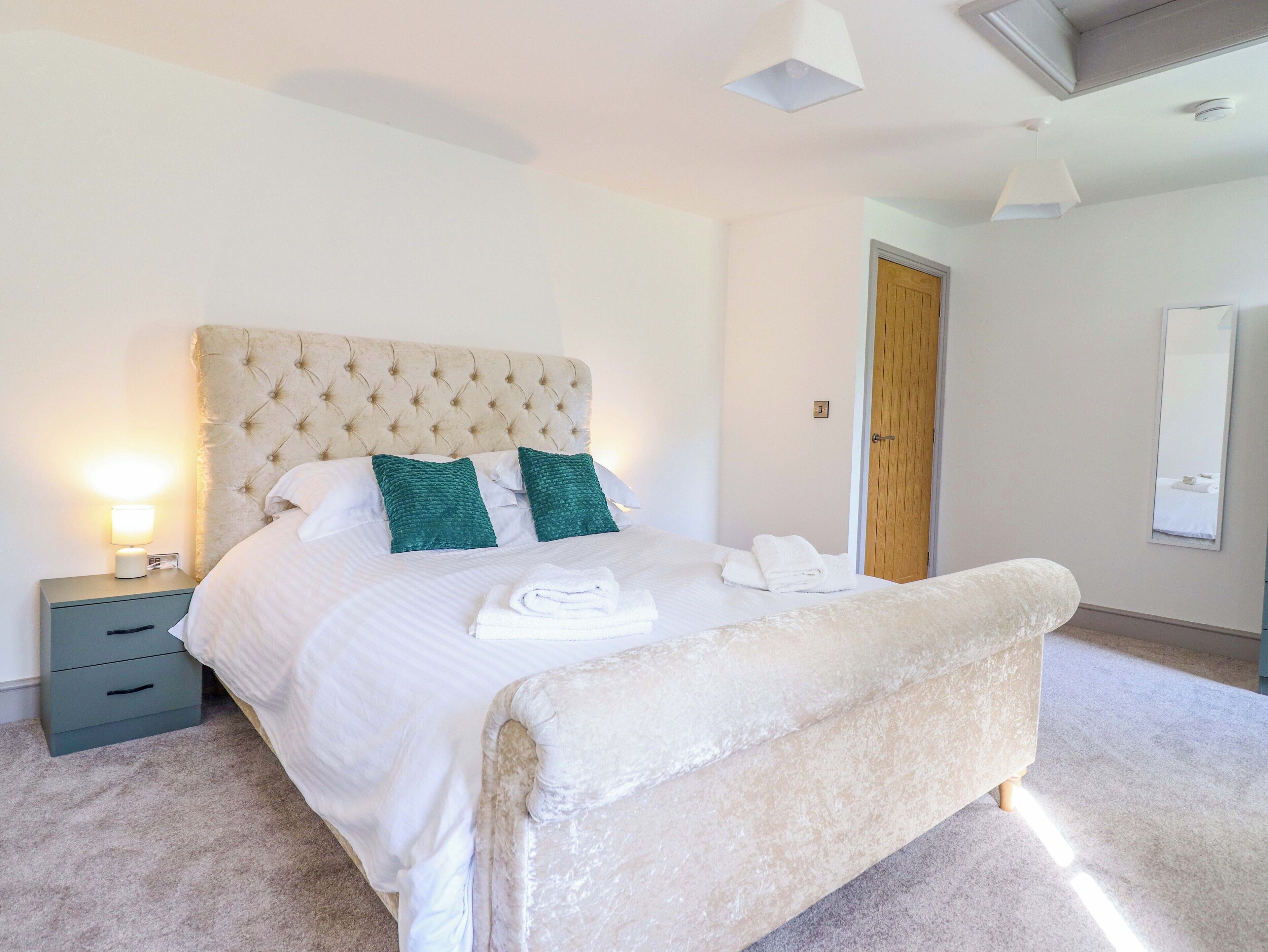 A neatly made bed with a tufted headboard, two pillows, and a folded towel on the side.
