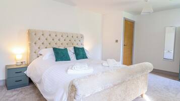 A neatly made bed with a tufted headboard, two pillows, and a folded towel on the side.