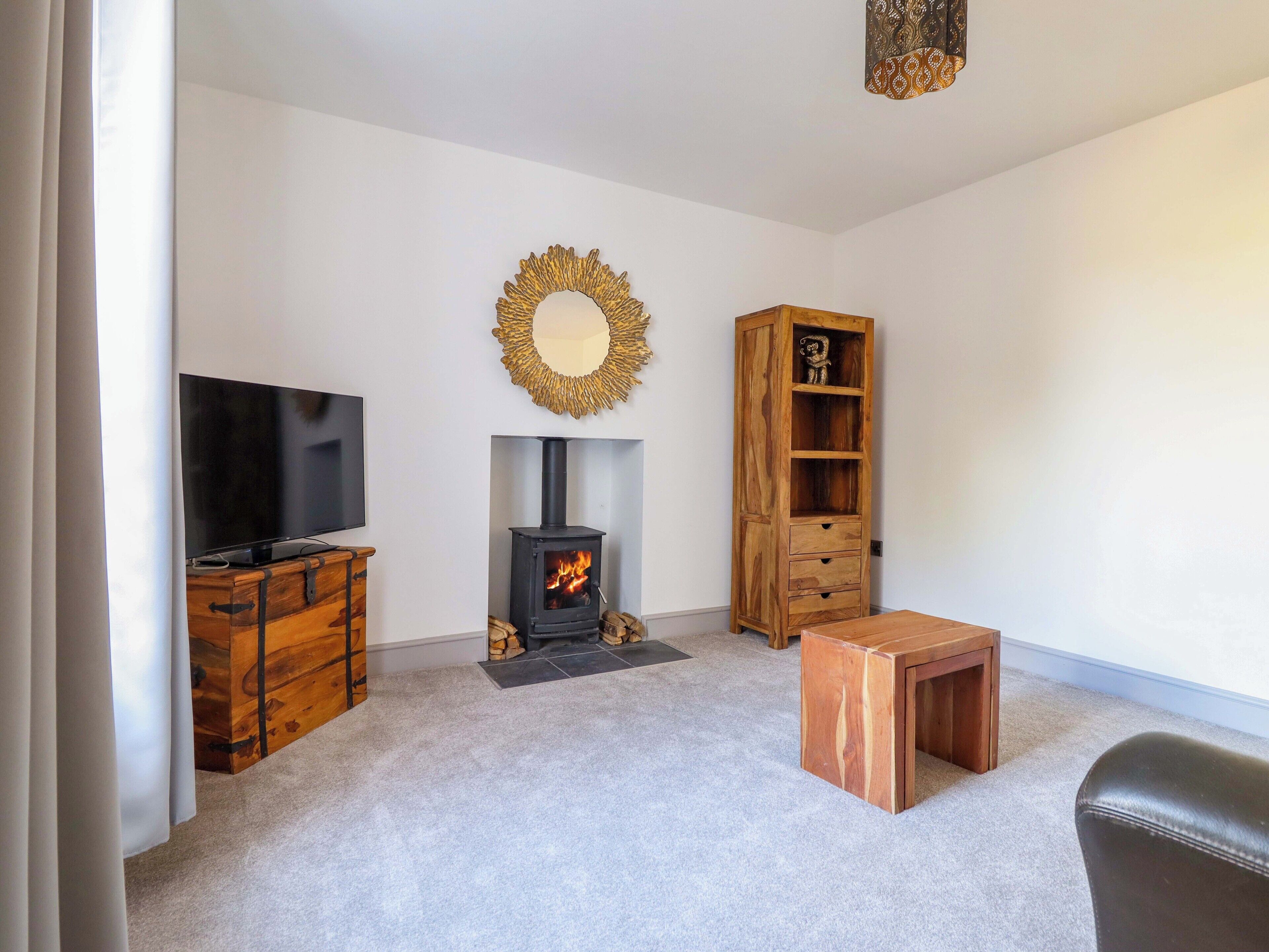 A living room with a fireplace, a television, a wooden cabinet, and a bookshelf.