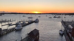 Una marina con barcos amarrados a muelles, un edificio de madera y un atardecer al fondo.