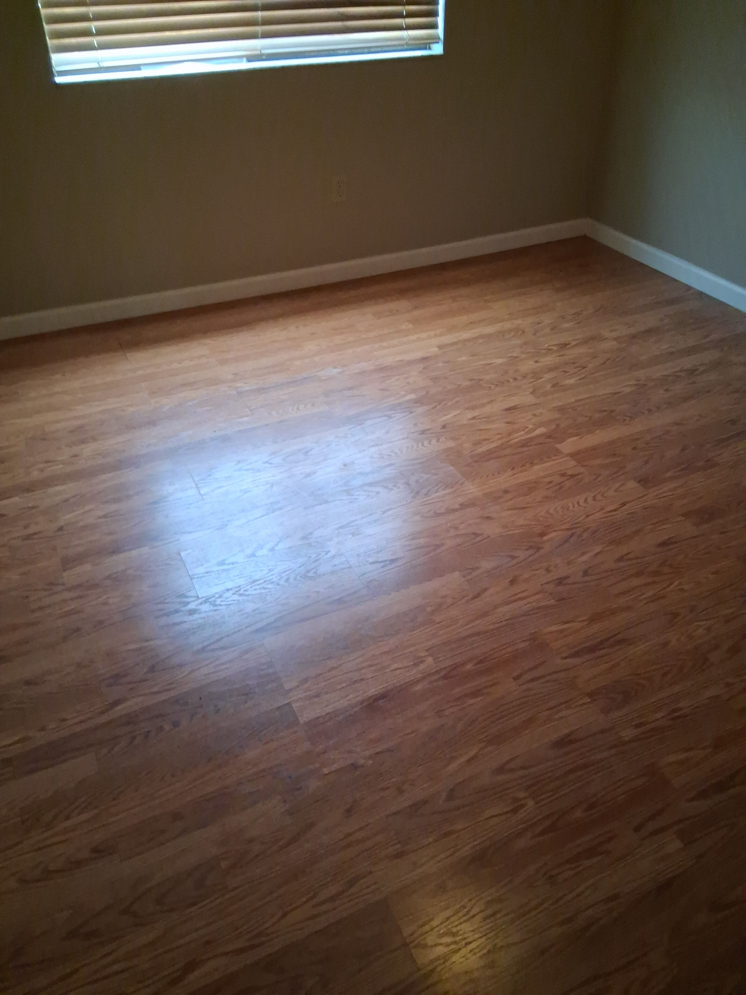 A room with wooden flooring and a window with blinds.