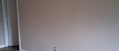 A room with wooden flooring, a beige wall, and a door.