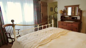 A bedroom with a bed, wooden chair, dresser, and a mirror. - The Cider Barn in Saint Austell (St Austell)