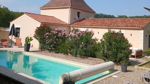 Eine Villa mit Swimmingpool, Außenbereich und einem Garten mit blühenden Pflanzen.