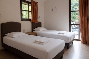 A hotel room with two beds, a window with curtains, a wooden nightstand, and a view of the outdoors. - Fronsac Deluxe Piscine 6p (Salles)