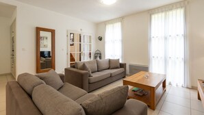 Een woonkamer met een modulaire bank, een kleinere bank, een salontafel en een spiegel.