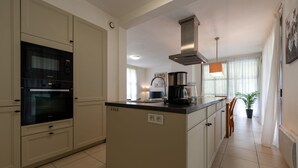 Een moderne keuken met een inbouwoven, een koffiezetapparaat en een raam met gordijnen.