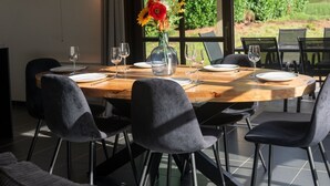 Un coin repas avec une table en bois, des chaises noires et un vase rempli de fleurs.