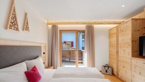 A bedroom with two beds, a wooden wardrobe, and a sliding glass door leading to a balcony. - Apartment 'Weissbrunn Alexander' with Mountain View, Shared Terrace and Wi-Fi (St. Maddalena)