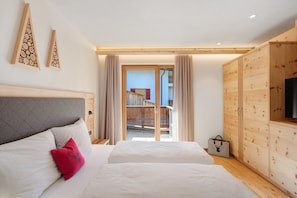 Ein Schlafzimmer mit zwei Betten, einem Holzschrank und einer Glastür zum Balkon.