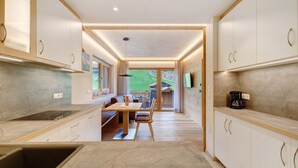 A modern kitchen with a dining area, wooden cabinets, and a view to the outside. - Apartment 'Weissbrunn Lisa' with Mountain View, Shared Terrace and Wi-Fi (St. Maddalena)