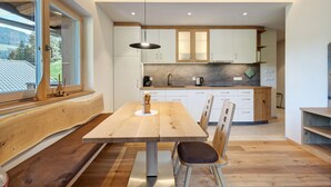 A modern kitchen with wooden cabinetry, a dining table with chairs, and a large window. - Apartment 'Weissbrunn Dominik' with Mountain View, Shared Terrace and Wi-Fi (St. Maddalena)