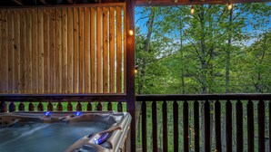 Un jacuzzi en una terraza de madera con vistas a un bosque.