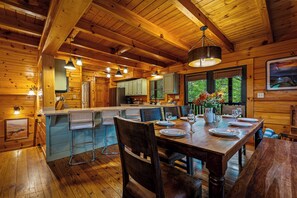 A wooden cabin interior with a dining area, kitchen, and bar. - Rivers Edge Luxury Sevierville Cabin - Sleeps 18 (Sevierville)