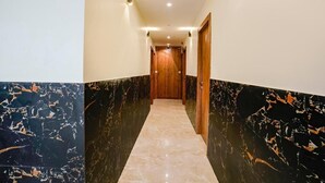 A hallway with marble walls and a wooden door at the end. - Antlers Hotel (Mumbai)