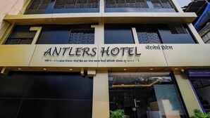 The exterior of Antlers Hotel with a signboard displaying the name and contact information. - Antlers Hotel (Mumbai)