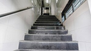 A set of black marble stairs with a metal handrail, leading to a landing with a door at the top. - Antlers Hotel (Mumbai)