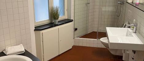 Un baño con bañera, lavamanos, ducha y ventana con vidrio esmerilado.