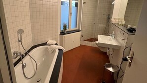 Un baño moderno con una bañera independiente, zona de ducha separada y tocador con espejo.