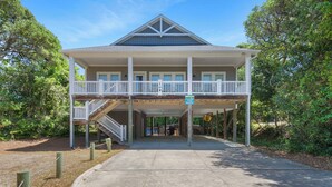 A two-story building with a balcony and a covered walkway. - 4 BR Cottage w/ Pool, Hot Tub, Tiki Bar, 2 King Suites - Walk to Beach (Emerald Isle)