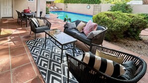 Un espace extérieur aménagé avec une terrasse, une piscine, des sièges et une vue sur une colline.