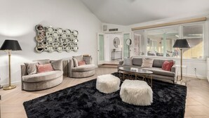 Un salon moderne avec deux canapés gris, un tapis noir à poils longs et un ventilateur de plafond.