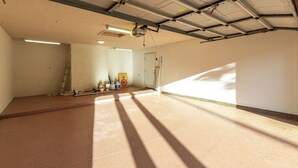 Une pièce spacieuse et vide, avec un plafond haut, une porte et une échelle.
