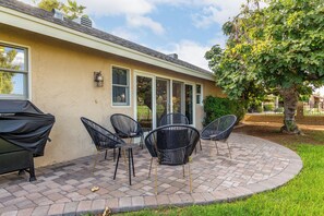 Un patio con mobiliario exterior y una parrilla.