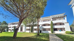 A multi-story building with a central courtyard, surrounded by trees and a stone pathway. - Magnificent T3 air-conditioned ground floor apartment with swimming pool and private beach ideal location (San-Nicolao)